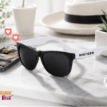 Custom promotional sunglasses with logo imprint styled next to a phone displaying Instagram likes and photos